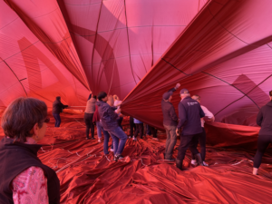 Team members pitch in as the red hot air balloon deflates